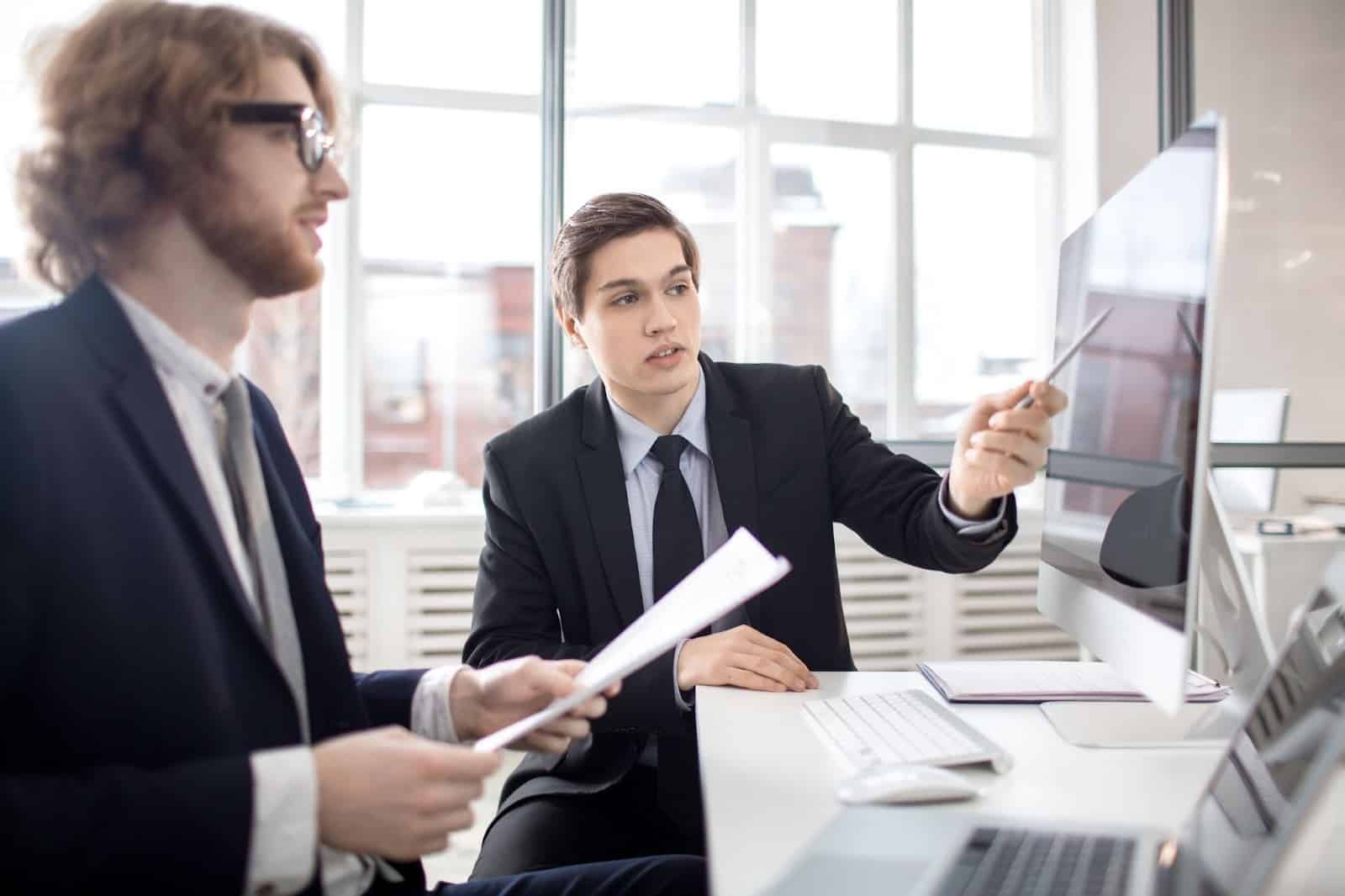 Two businessmen discussing project plans at modern office desk